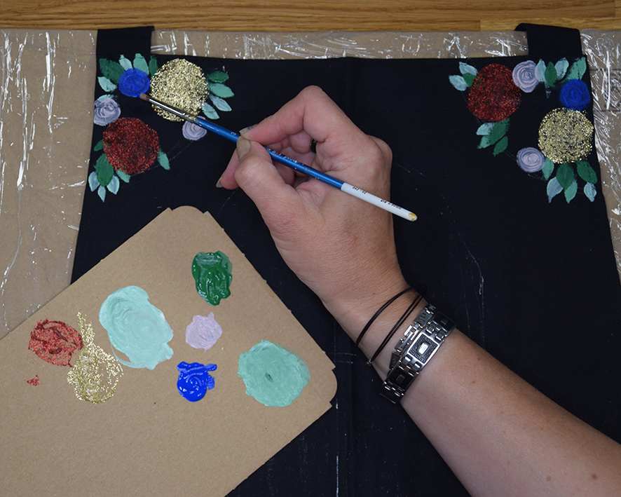 Žena maľuje na listočky vrstvu farebných kruhov symbolizujúcich základ pre kvety.